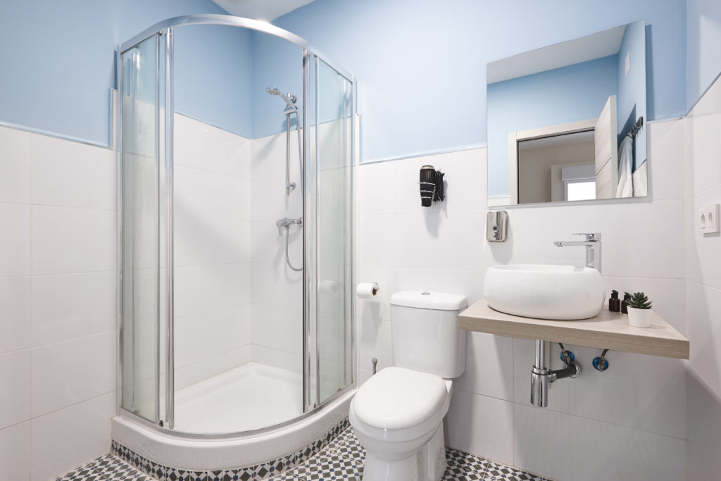 Bathroom with shower cabin, sink and basin. Hotel indoor