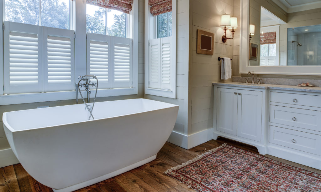 Luxury bathroom with large white tub, beautiful cabinets, and sh
